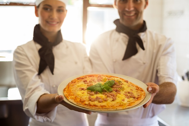 Retrato de dos chef presentando una pizza