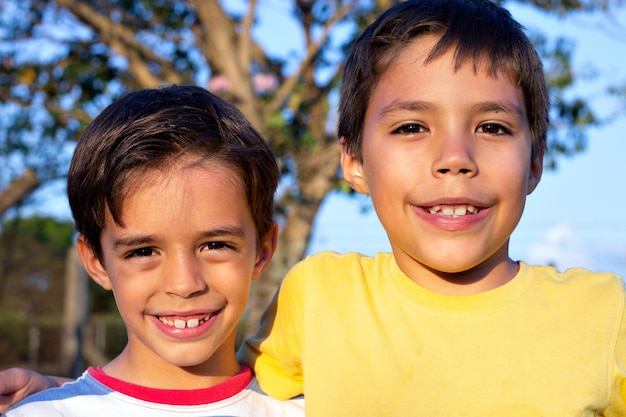 retrato de dos chicos lindos sonriendo abrazándose al aire libre