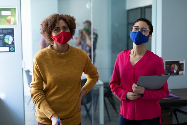 Retrato de dos colegas de raza mixta que usan máscaras en el cargo. higiene en el lugar de trabajo durante la pandemia del coronavirus covid 19.