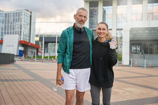 Retrato de dos deportistas de mediana edad activos en ropa deportiva caminando juntos al aire libre después