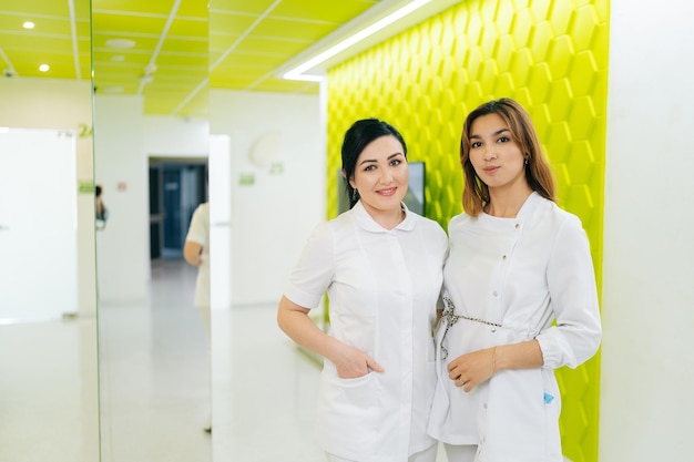 Retrato de dos enfermeras jóvenes con trajes médicos sonriendo mirando a la cámara posando