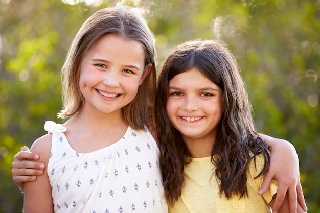 retrato, de, dos, feliz, niñas jóvenes, se abrazar, aire libre