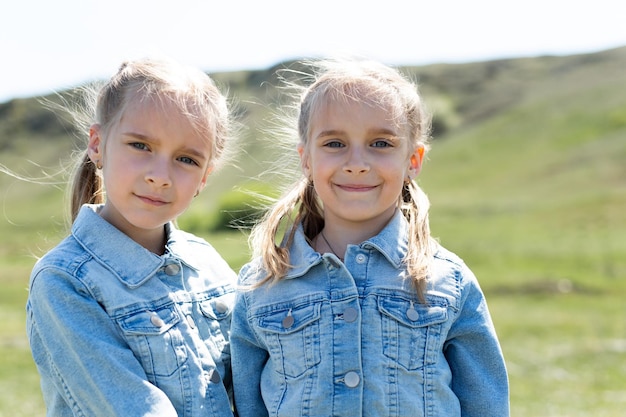 Retrato de dos hermanas gemelas que se abrazan en un prado en la naturaleza