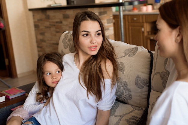 Retrato de dos hermanas y una niña sentada en el sofá