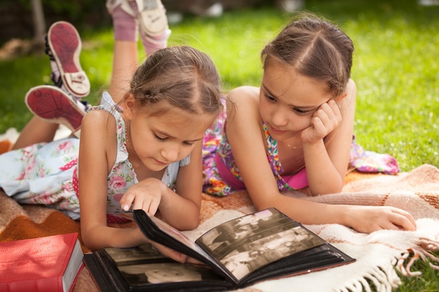 Retrato de dos hermanitas mirando el álbum de fotos en el parque