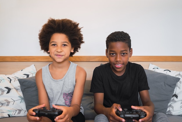 Retrato de dos hermanos afroamericanos jugando videojuegos en casa. concepto de estilo de vida y tecnología.