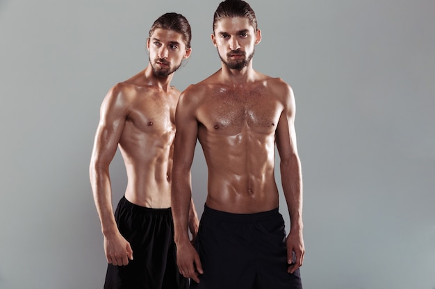 Foto retrato de dos hermanos gemelos descamisados musculosos confiados