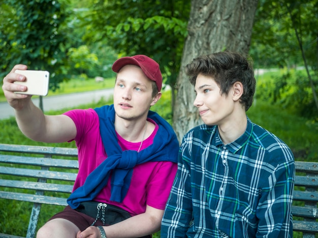 Retrato de dos hermanos jóvenes atractivos haciendo un autorretrato usando un teléfono al aire libre