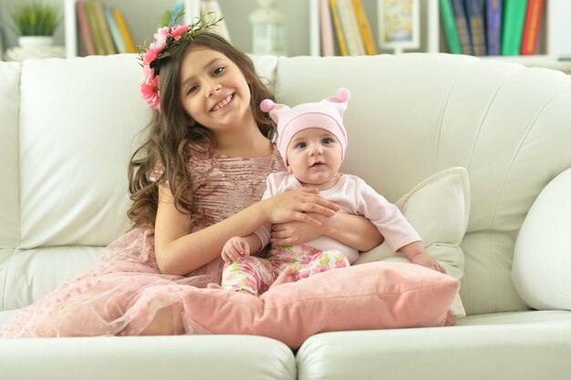 Retrato de dos hermosas hermanas lindas posando en el sofá en casa