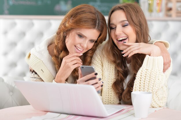 Retrato de dos hermosas mujeres jóvenes usando laptop