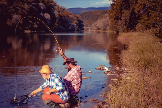 Foto retrato de dos hombres alegres pescando pesca con mosca fin de semana perfecto ido a pescar tiempo de fin de semana pescador con caña unidos con la naturaleza en el lago