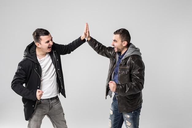 Foto retrato de dos hombres jóvenes felices dando cinco aislado sobre fondo blanco.