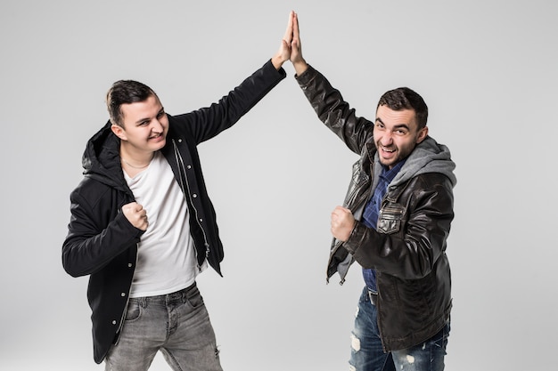 Retrato de dos hombres jóvenes felices dando cinco aislado sobre fondo blanco.