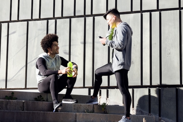 Retrato de dos hombres jóvenes en forma y deportivos relajarse y estirarse después de hacer ejercicio.