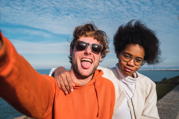 Retrato de dos jóvenes amigos pasando un buen rato juntos y tomando un selfie al aire libre.