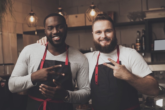 Retrato de dos jóvenes baristas masculinos en el espacio de trabajo