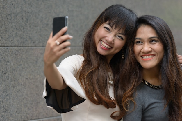 Retrato de dos jóvenes empresarias asiáticas juntas en la ciudad al aire libre