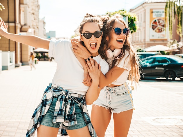 Retrato de dos jóvenes hermosas mujeres hipster sonrientes en ropa de camiseta blanca de verano de moda