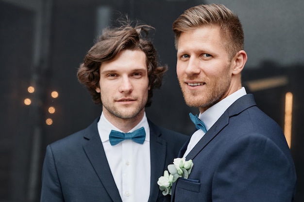 Retrato de dos jóvenes sonrientes vistiendo trajes durante la ceremonia de boda concepto de matrimonio entre personas del mismo sexo