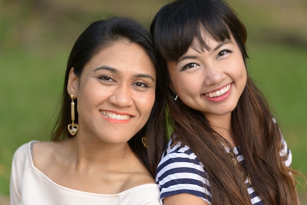 Retrato de dos mujeres asiáticas jóvenes juntos relajándose en el parque al aire libre