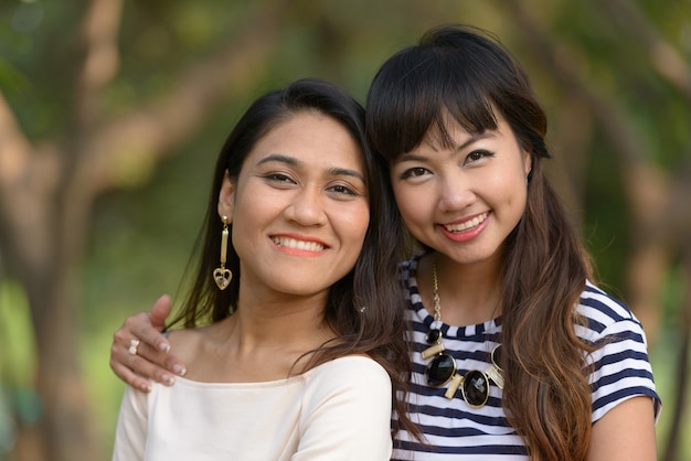 Retrato de dos mujeres asiáticas jóvenes juntos relajándose en el parque al aire libre