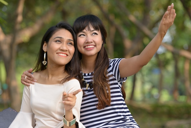 Retrato de dos mujeres asiáticas jóvenes juntos relajándose en el parque al aire libre