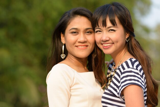 Retrato de dos mujeres asiáticas jóvenes juntos relajándose en el parque al aire libre