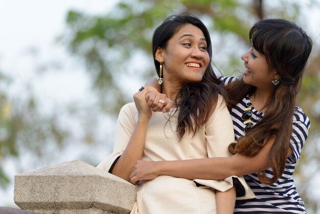 Retrato de dos mujeres asiáticas jóvenes juntos relajándose en el parque al aire libre