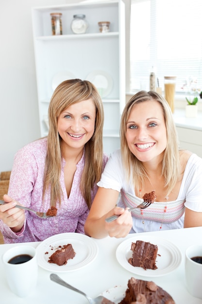 Retrato de dos mujeres comiendo un pastel de chocolate durante la hora de la merienda