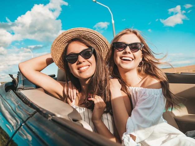 Retrato de dos mujeres hipster hermosa y sonriente joven en coche descapotable