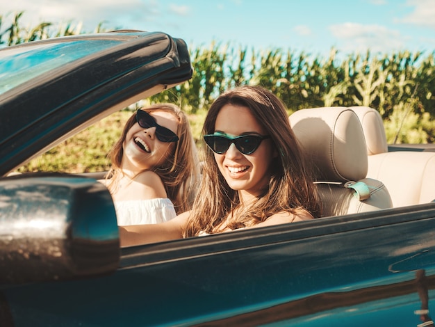 Retrato de dos mujeres hipster hermosa y sonriente joven en coche descapotable