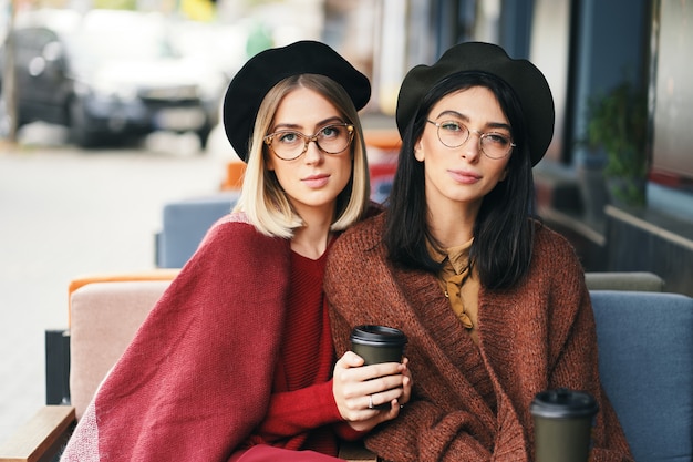 Retrato de dos mujeres jóvenes en un café al aire libre, tomando café