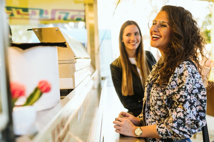 Foto retrato de dos mujeres jóvenes que visitan comer mercado en la calle.