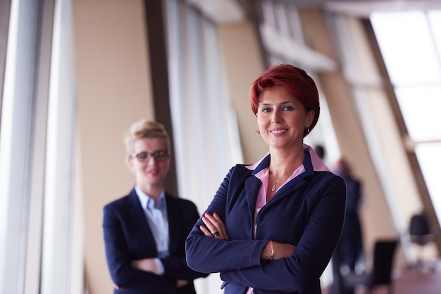 retrato de dos mujeres de negocios corporativos en el interior de la oficina moderna y luminosa de pie en grupo como equipo