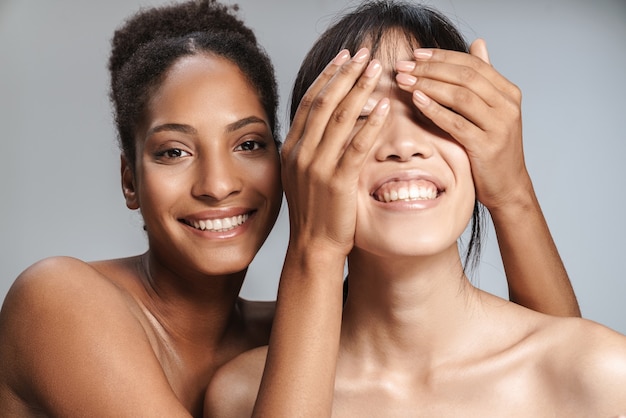 Retrato de dos mujeres semidesnudas multinacionales posando juntas y burlándose