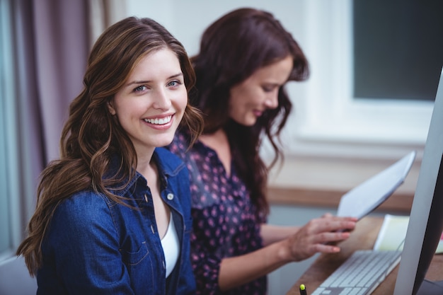 Retrato de dos mujeres sentadas frente a la computadora