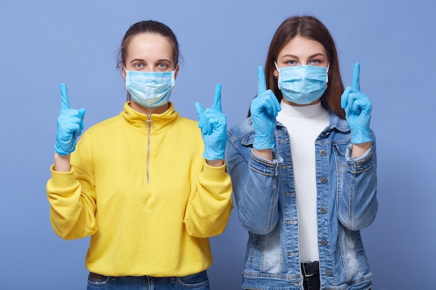 Foto retrato de dos mujeres vestidas con ropa casual y máscaras de salud de cerca