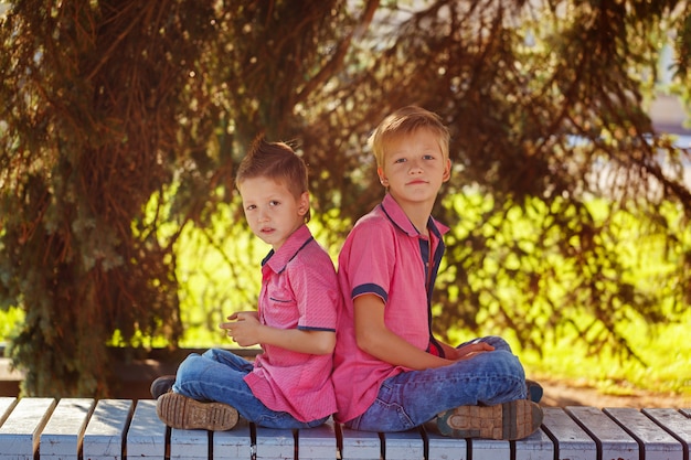 Retrato dos niños pequeños que juegan juegos en el teléfono móvil en soleado