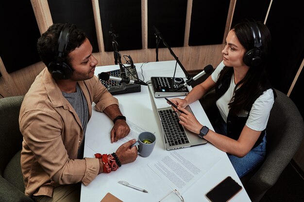 Foto retrato de dos presentadores de radio, un joven y una mujer discutiendo varios temas mientras moderaban un concierto