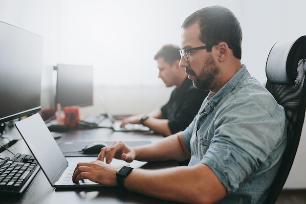 Retrato de dos programadores masculinos profesionales que trabajan en computadoras en diversas oficinas Desarrollo de tecnologías de TI modernas de aplicaciones de programas de inteligencia artificial y concepto de videojuegos