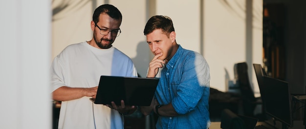 Foto retrato de dos programadores masculinos profesionales que trabajan en computadoras en diversas oficinas desarrollo de tecnologías de ti modernas de aplicaciones de programas de inteligencia artificial y concepto de videojuegos