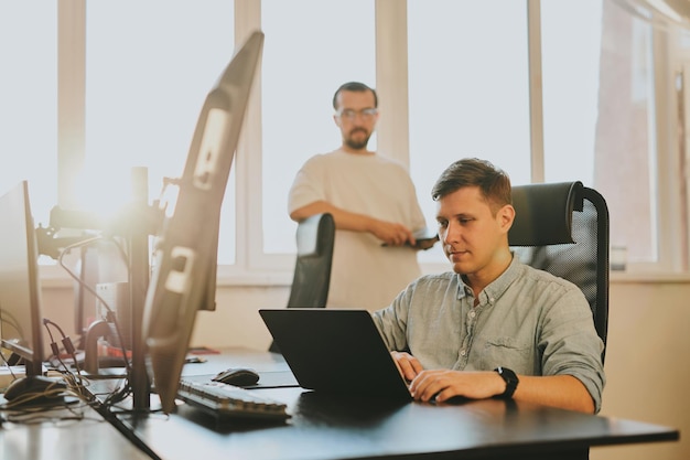 Retrato de dos programadores masculinos profesionales que trabajan en computadoras en diversas oficinas Tecnologías informáticas modernas Desarrollo de programas de inteligencia artificial Aplicaciones y concepto de videojuegos