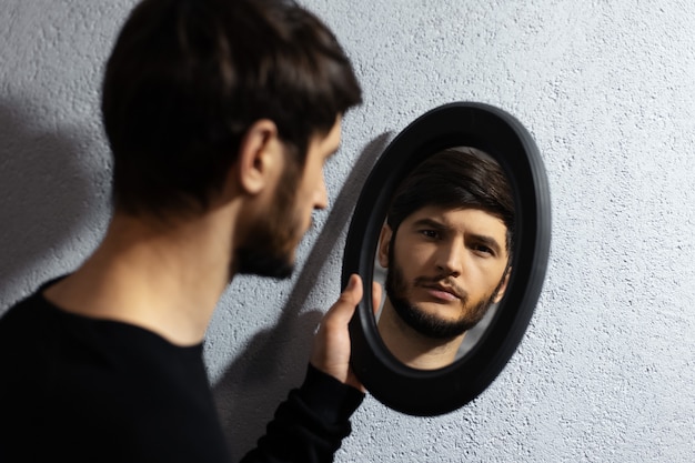 Retrato dramático de jovem olhando no espelho.