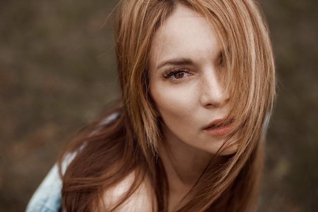 Retrato dramático de uma menina de cabelo comprido ruivo com olhos grandes.