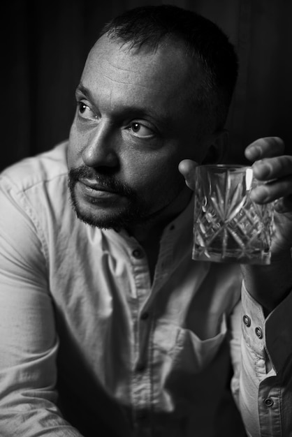 Foto retrato dramático de un hombre adulto con un vaso en la mano fotografía de estudio imagen en blanco y negro