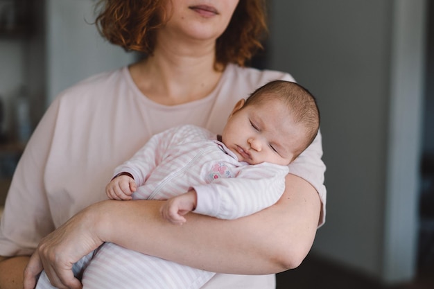 Retrato de dulce bebé durmiendo en las manos de la madre Mamá cariñosa cuidando a su bebé recién nacido en casa Madre abrazando a su pequeña niña de 1 mes