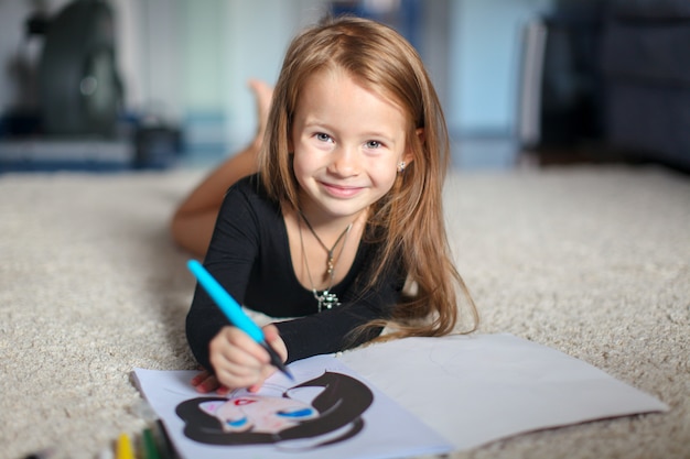 Retrato de una dulce niña encantadora que dibuja con su colorante en casa