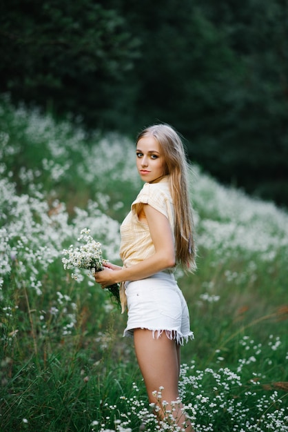 Retrato de una dulce niña suave en un campo de flores blancas