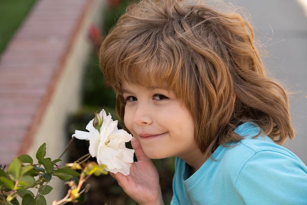 Retrato de un dulce niño pequeño que disfruta del aroma de las flores divirtiéndose en el parque de primavera