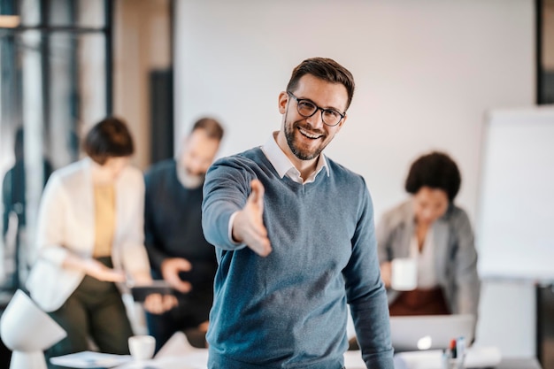 Retrato de un ejecutivo feliz presentándose mientras está de pie en la oficina con sus colegas